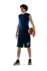 Full-length portrait of young muscular basketball player posing isolated on white background....