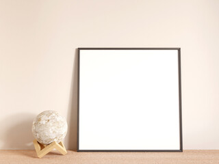 Modern and minimalist square black poster or photo frame mockup on the living room wooden table. 3d rendering.
