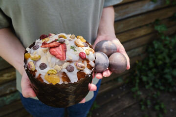 Homemade traditional Easter sweet bread and eggs in the hands of a girl. Delicious pastries for Easter. Confectionery