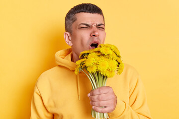 Portrait of Caucasian sick ill man wearing casual style hoodie posing isolated over yellow...