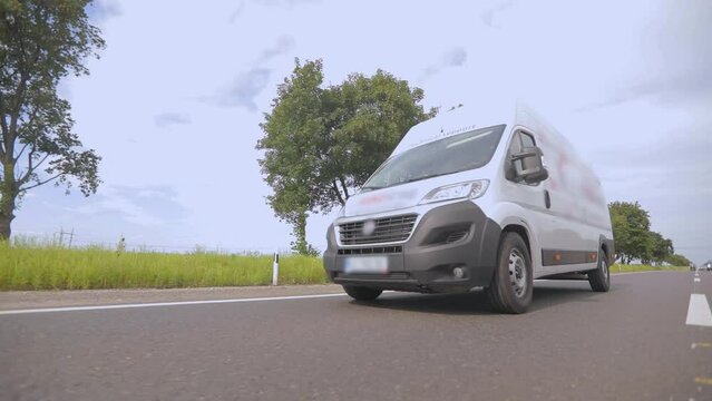 A white cargo bus is driving along the highway. Truck driving on a modern road