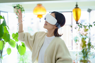 部屋でVRゴーグルを装着して、手探りをする女性