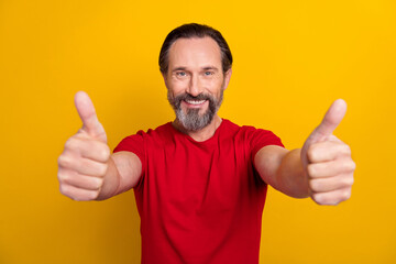 Photo of impressed mature brunet man thumb up wear red t-shirt isolated on yellow color background