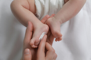 Obraz na płótnie Canvas Mother applying body cream on her little baby, top view