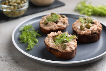 Slices of bread with delicious pate, capers and dill on light grey table, closeup