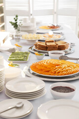 Clean dishware and different meals for breakfast on white table indoors. Buffet service