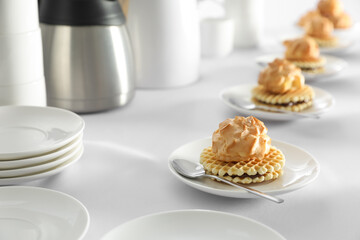 Many delicious waffles with cream served on white table for coffee break