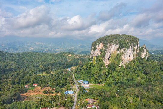 Aerial view to the Limestone hill  Bukit Batu Kapur at Cinta Manis, Pahang, Malaysia. A mountain rock out of nowhere in the middle of the Malaysian rainforest. Green overgrown with jungle vegetation.