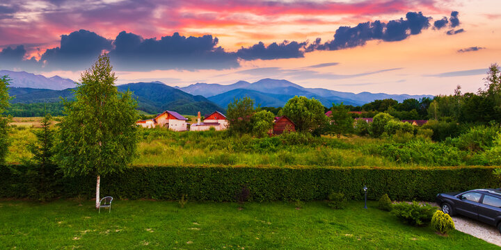 summer vacations in rural area of romania. beautiful countryside landscape with fagaras ridge in the distance. nature scenery with fluffy clouds on the sky at dusk
