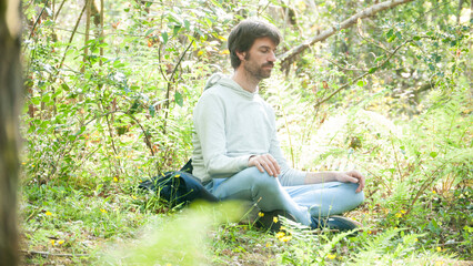 Naklejka na ściany i meble Hombre blanco sentado en el bosque meditando