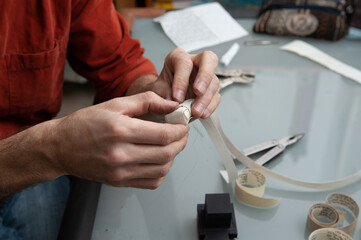 A Jewish scribe binds a scroll with Hebrew verses from the Bible before inserting into the boxes...