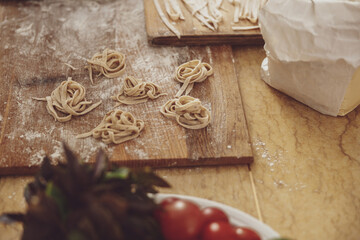 Kitchen wooden board in flour with homemade noodles laid out on it