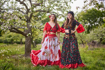two dancers in traditional gypsy dresses dance in nature on a spring day - obrazy, fototapety, plakaty