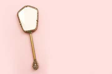 Top view image of vintage hand mirror over pink pastel background