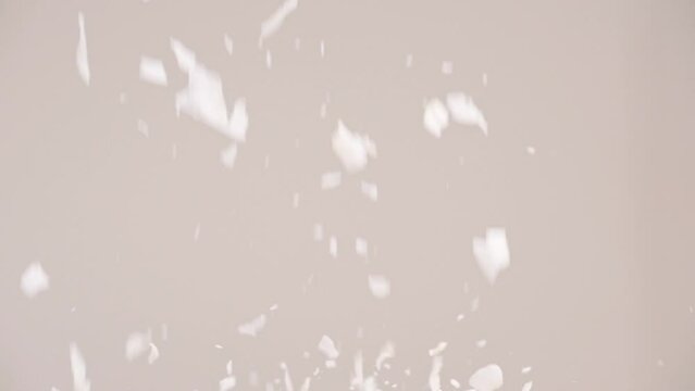 Coconut flakes raining down and bouncing in slow motion with gray backdrop 4k