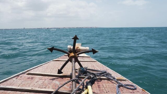 Bow deck of seaborne wooden boat with grappling anchor and rope.