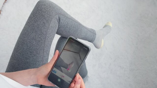 The girl examines the leg in virtual shoes. Online shoe fitting. Virtual fitting room through smartphone camera