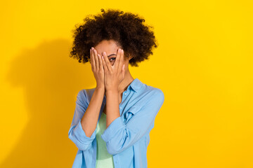 Photo of adorable shy lady palms close face eyes peek fingers wear jeans shirt isolated yellow...