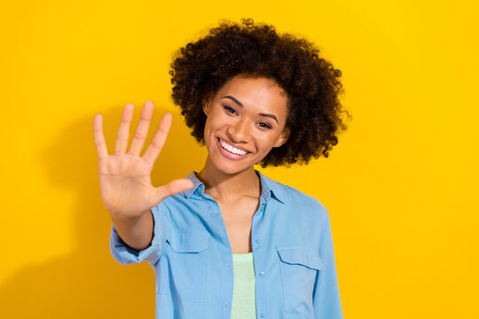Photo of positive cheerful pretty cute lady show palm high five gesture wear denim shirt isolated yellow color background