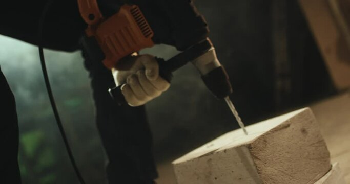 A worker drills aerated concrete with an electric drill.