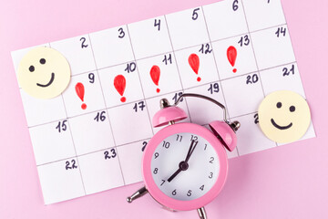Calendar of women's menstruation, funny emoticons and an alarm clock (clock) on a pink background. Critical days, women's health. Mood swings during PMS.