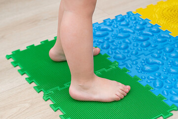 Children's little feet stand on multi-colored massage mats