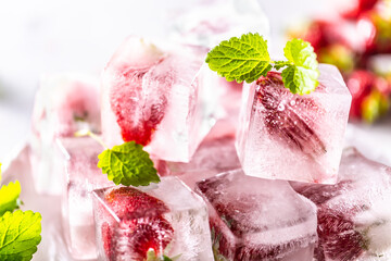 Strawberries frozen in ice cubes with mellisa leaves