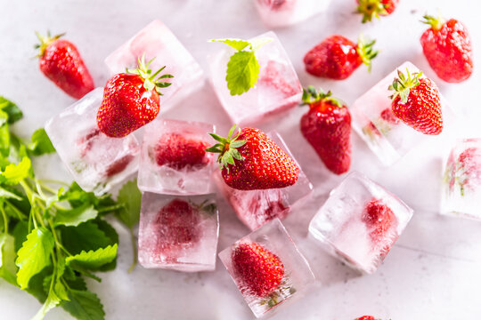 Strawberries frozen in ice cubes with mellisa leaves - Top of view.