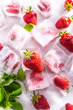 Strawberries frozen in ice cubes with mellisa leaves - Top of view.