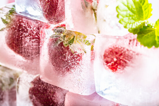 Fresh strawberries frozen in ice blocks with melissa leaves
