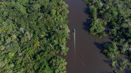 Photograph on the Amazon River of a fishing boat among the mangroves. Lush jungle. Drone photography