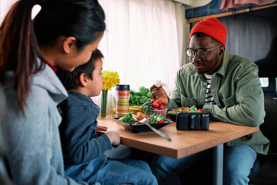 A Hipster Multicultural Family Is Eating Lunch In A Van.