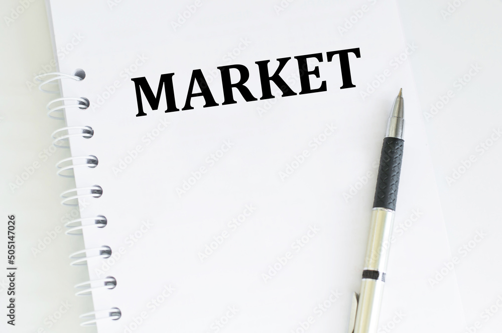 Poster market text on a white notepad next to the pen is isodized lying on the table