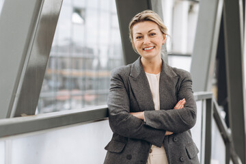 Portrait of a mature business woman smiling with emotions on the modern office and urban background