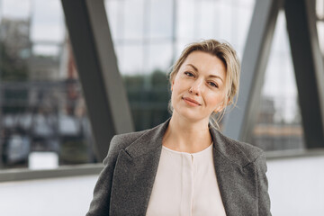 Portrait of a mature business woman smiling with emotions on the modern urban and office buildings...