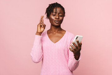 Black woman making gesture for good luck while using mobile phone