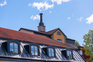 Fototapeta na wymiar Roofs, dorms and chimney of old 1700s houses a sunny day in Stockholm