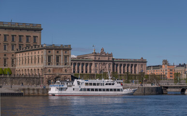 Fototapeta na wymiar Commuting boat at the pier Strömkajen and the Swedish Parliament building on the island Helgeandsholmen a sunny day in Stockholm 