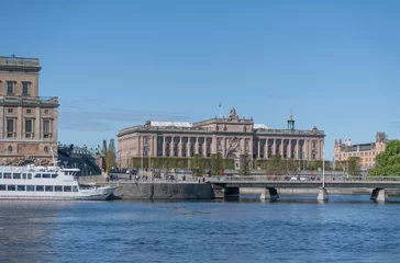 Papier Peint photo Stockholm Commuting boat at the pier Strömkajen and the Swedish Parliament building on the island Helgeandsholmen a sunny day in Stockholm 