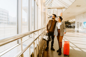 Young indian couple looking in window together at airport