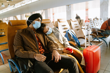 Indian couple wearing face masks sleeping while sitting in airport