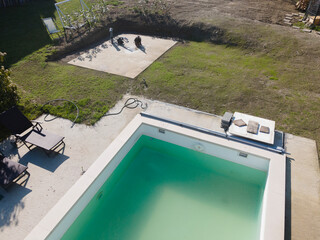 Obraz premium Drone flight over pool in the middle of greenery, fresh grass grown and the pool is not yet cleaned