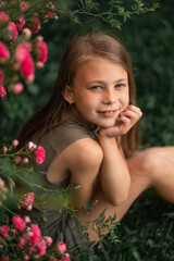 Obraz na płótnie Canvas very beautiful little girl near the roses