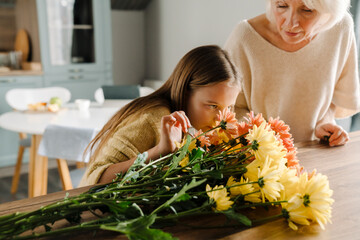 White senior woman making bouquet with her granddaughter in kitchen