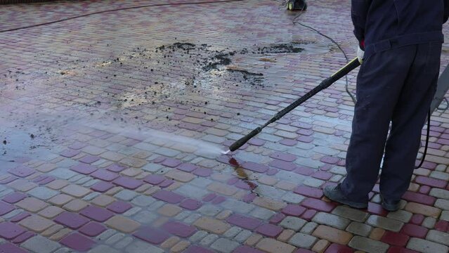 Cleaning backyard paving tiles with high pressure washer. Spring clean up. Cleaning dirty backyard paving tiles with pressure washer cleaner. Spring clean up