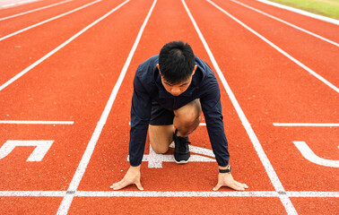 Obraz premium Young handsome chinese man doing star pose before running exercise on track in sport stadium. Challenge race of athletes running in the starting point