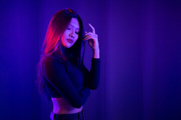 Stylish sexy woman in trendy. Beautiful young asian woman standing pose with neon light. Asia Pretty asian female in the dark room. Fashion shot.