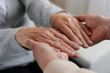 Mature female in elderly care facility gets help from hospital personnel nurse. Cropped shot of...