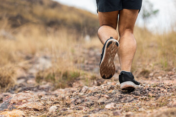 Close up foot trail runner man running on rocky mountain. Athlete jog exercising outdoor for...