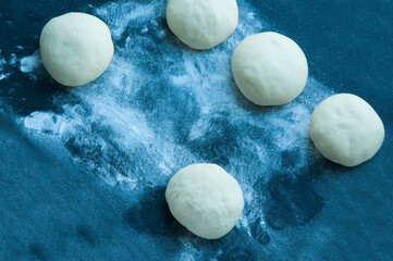 cakes with dough on a board with flour. the concept of cooking pies. shaped loaves of bread on a black background.